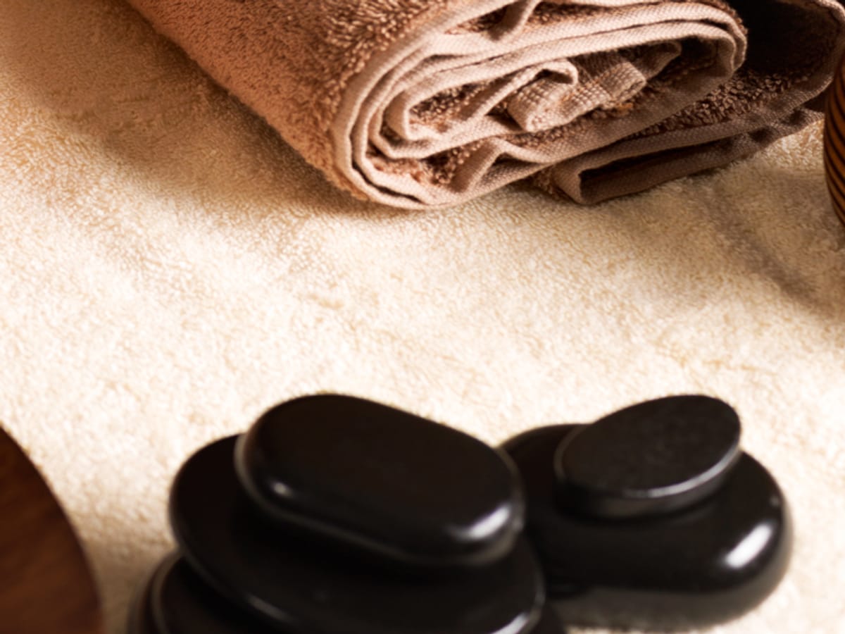Heated basalt stones and folded towels on cream linen